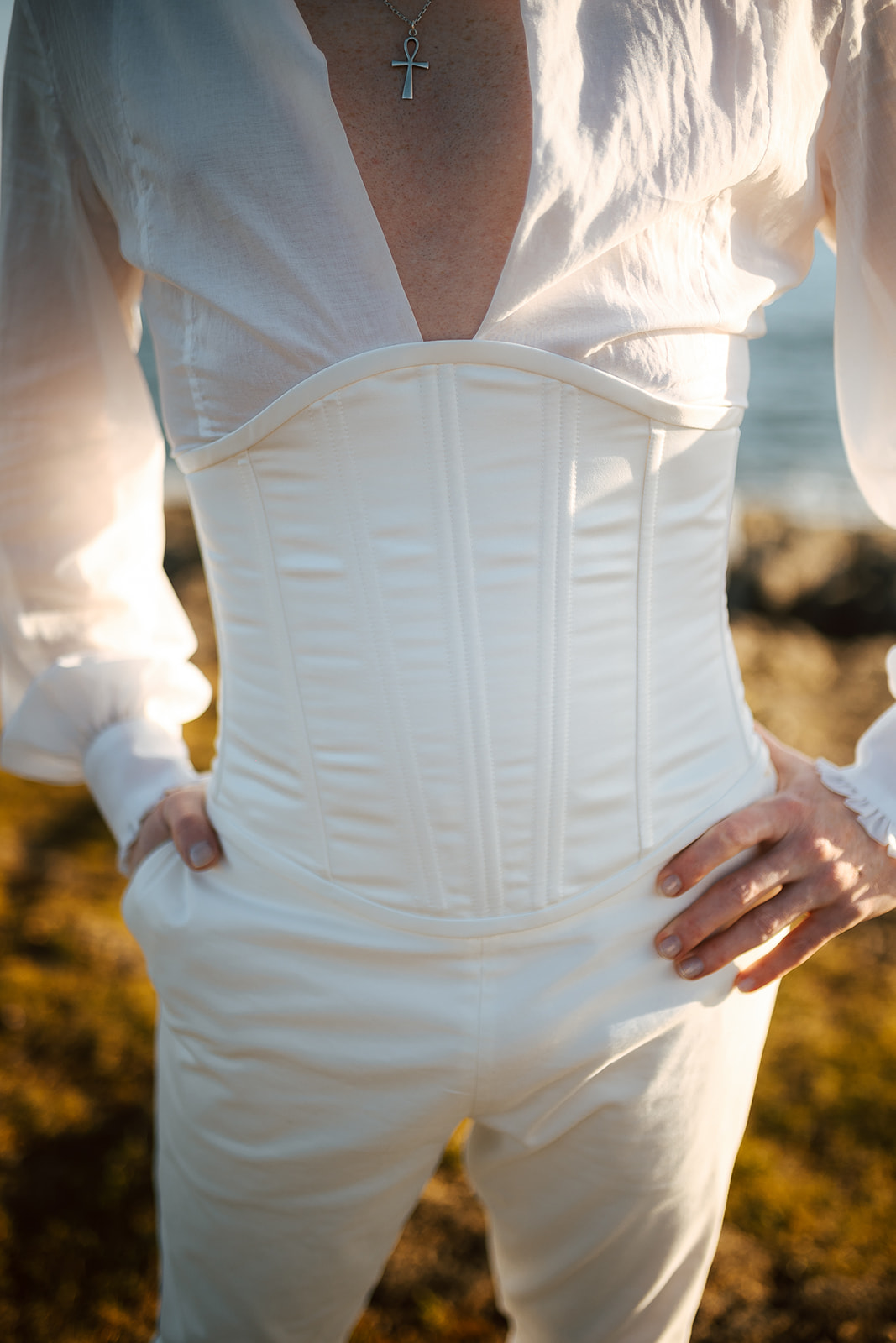 Homme portant un costume de mariage avec corset sur-mesure en bord de mer.